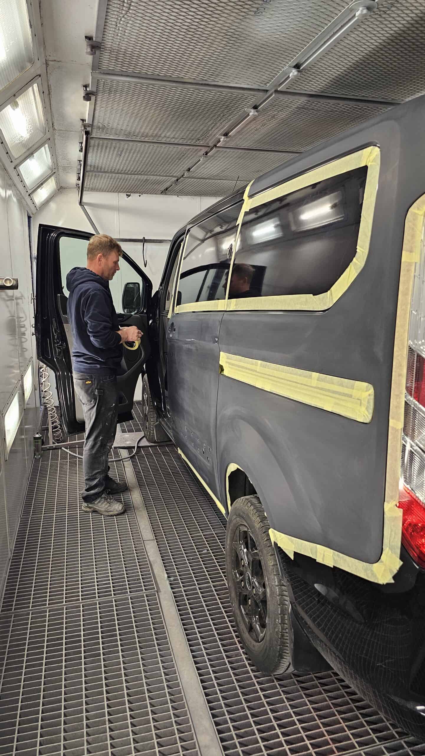 Technician inspecting vehicle during car accident repair in workshop.