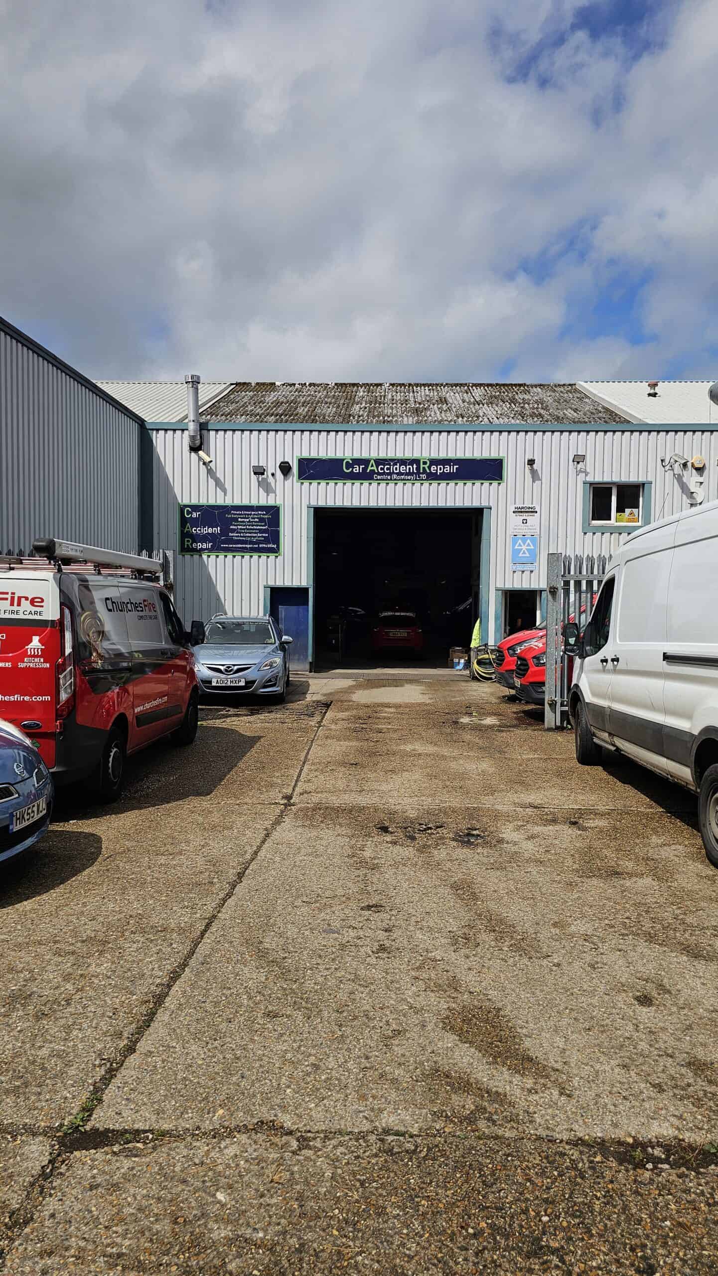 Car accident repair garage with vehicles and equipment outside.