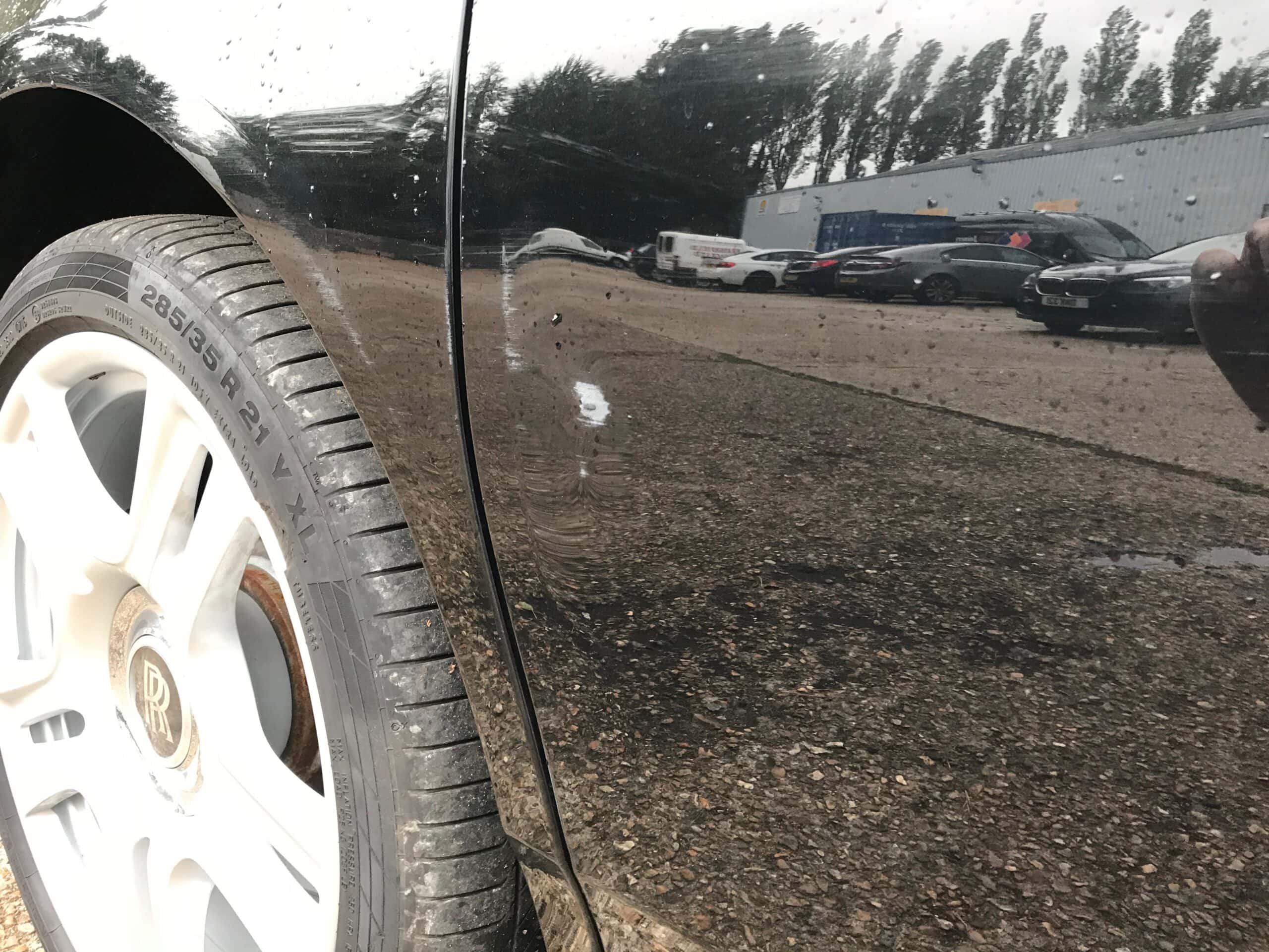 Accident damage repair on a black car showing scratches and dents. Skilled technicians restore vehic.