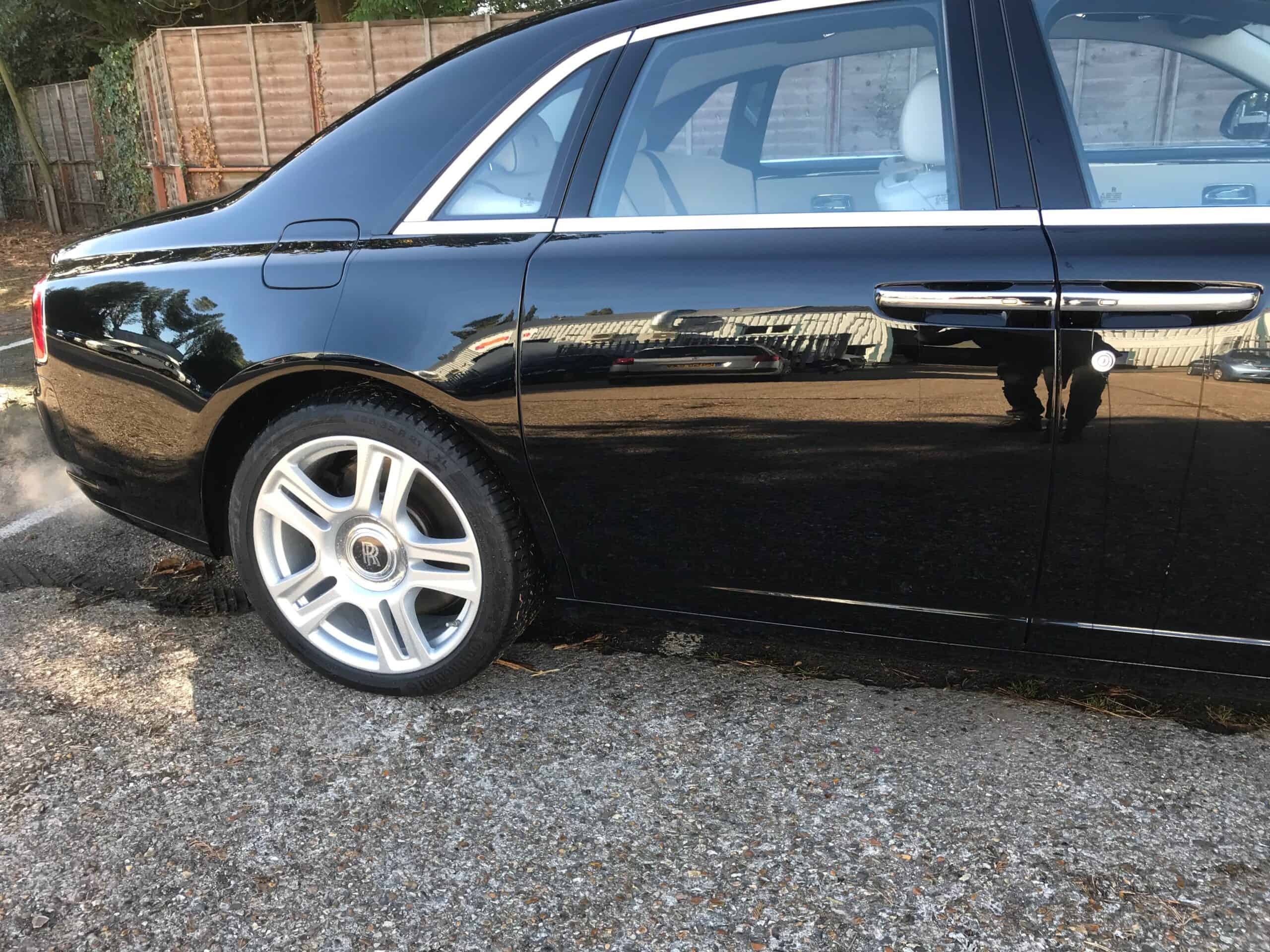 Black luxury sedan with minor damage on the side door, ready for repair.