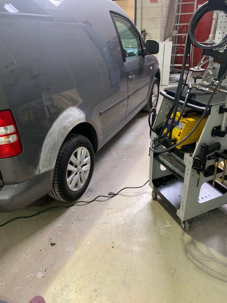 Vehicle repair in progress for a grey van at a collision repair workshop.